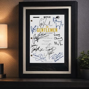 May include: A framed script cover for the television series The Gentlemen, featuring the Netflix and Miramax logos, gold text, and multiple black and blue ink signatures. The document is presented in a black frame with a white matting border.