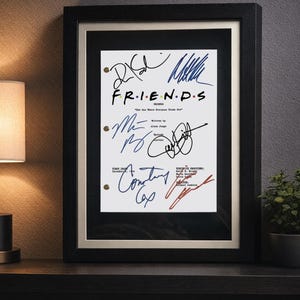 May include: A framed script cover for the television show Friends, titled The One Where Everyone Finds Out. The white paper features black text and multiple signatures in blue, black, and red ink, all enclosed within a black frame with a mat.