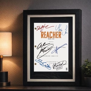 Pode incluir: Impressão emoldurada com a palavra "REACHER" em laranja e várias assinaturas em tinta azul e preta. A impressão tem um fundo branco e está emoldurada em uma moldura preta. A moldura é exibida em uma superfície escura.
