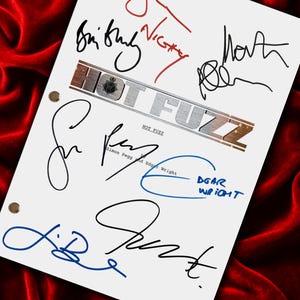 May include: A white sheet featuring multiple signatures in black, red, and blue ink. The film title "HOT FUZZ" is printed in silver. The sheet has ring binder holes and is set against a red velvet background.