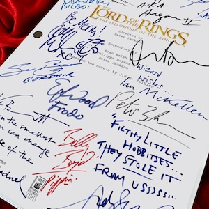 Puede incluir: Un guion blanco de "El Se&ntilde;or de los Anillos: La Comunidad del Anillo" con m&uacute;ltiples firmas en tinta azul y roja. El t&iacute;tulo est&aacute; en letras doradas. El guion est&aacute; sobre un fondo de terciopelo rojo.