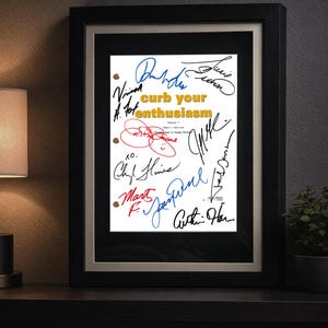 May include: A framed script cover for Curb Your Enthusiasm, Season 7, Show 1 Outline, titled "Funkhouser's Crazy Sister." The white paper features yellow text and multiple signatures in black, blue, and red ink, enclosed in a black frame.