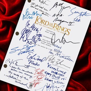 May include: A white script featuring signatures from the cast of "The Lord of the Rings: The Fellowship of the Ring." The script includes the film's title, character names, and quotes, all written in various colors of ink.