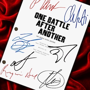 Puede incluir: Un guion blanco con el título "ONE BATTLE AFTER ANOTHER" en negrita negra, con múltiples firmas en tinta azul y roja. El guion está sobre un fondo de terciopelo rojo.