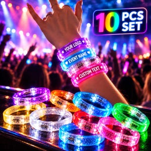 Puede incluir: Un juego de 10 pulseras LED luminosas en varios colores, incluyendo morado, azul, rosa, naranja, amarillo y verde. Las pulseras tienen una textura brillante y un pequeño compartimento para pilas. Algunas muestran el texto YOUR LOGO, EVENT NAME y CUSTOM TEXT.