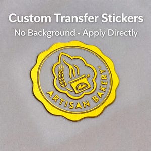 Könnte beinhalten: Ein goldfarbener individueller Transferaufkleber mit dem Text "Artisan Bakery" in einem kreisförmigen Design. Der Aufkleber hat eine Weizenähre und eine Brotbackofen-Grafik. Der Text "Custom Transfer Stickers" und "No Background • Apply Directly" stehen oben.