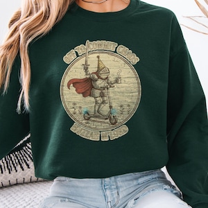 May include: Dark green sweatshirt with a circular graphic of a knight on a scooter, holding a sword and a coffee cup. The graphic includes the text "OFF TO COMMIT CHAOS" and "BUZZIN' AROUND".