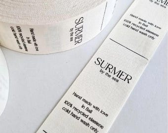 May include: A roll of off-white fabric ribbon with the text "SURMER by the sea" printed in black. The ribbon also includes text stating "Hand made with love in Bali, 100% recycled elastene, cold hand wash only."