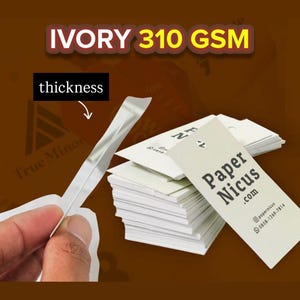 May include: A stack of white rectangular business cards labeled Paper Nicus .com with contact details. A single card is held up to show its thickness. The text IVORY 310 GSM is displayed at the top, and an arrow points to the card edge labeled thickness.
