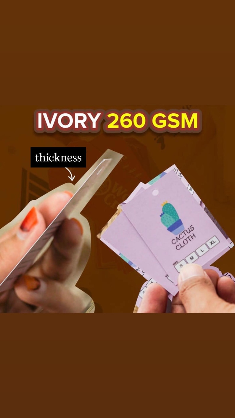 May include: A light purple rectangular clothing tag featuring a green cactus illustration, the text CACTUS CLOTH, and size options S, M, L, and XL. The tag is made of ivory 260 GSM paper, with an arrow pointing to the edge to indicate thickness.