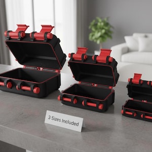 Może przedstawiać: Trzy czarne i czerwone skrzynie do przechowywania w różnych rozmiarach są wyświetlane. Skrzynie mają czerwone zatrzaski i uchwyty, a pokrywy są otwarte. Mały znak głosi "3 rozmiary w zestawie". Skrzynie są prawdopodobnie przeznaczone na narzędzia lub sprzęt.