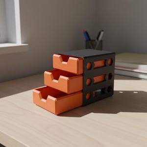 Peut inclure: Un organiseur de bureau à trois niveaux avec des tiroirs orange et un cadre noir. L'organisateur est posé sur un bureau en bois de couleur claire. Des stylos et des cahiers sont visibles en arrière-plan. Les tiroirs ont une découpe pour un accès facile.