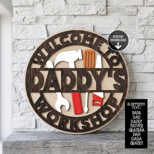 May include: A wooden sign with the words "WELCOME TO DADDY'S WORKSHOP" cut out in a circular design. The sign features various tool cutouts and a "DIGITAL DOWNLOAD" icon. The sign is light brown with dark brown lettering.