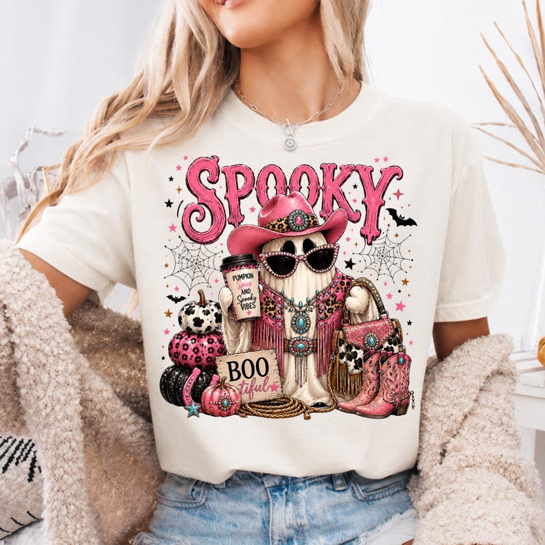 Western cowgirl Halloween design displayed on a shirt with a turquoise glam ghost, leopard-print details, spiderwebs, pumpkins, western accessories, and spooky typography.