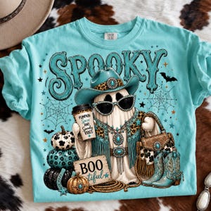 Western Halloween ghost design featuring bats, spiderwebs, patterned pumpkins, cowboy boots, turquoise stars, BOOtiful sign, and Pumpkin Spice and Spooky Vibes coffee cup.