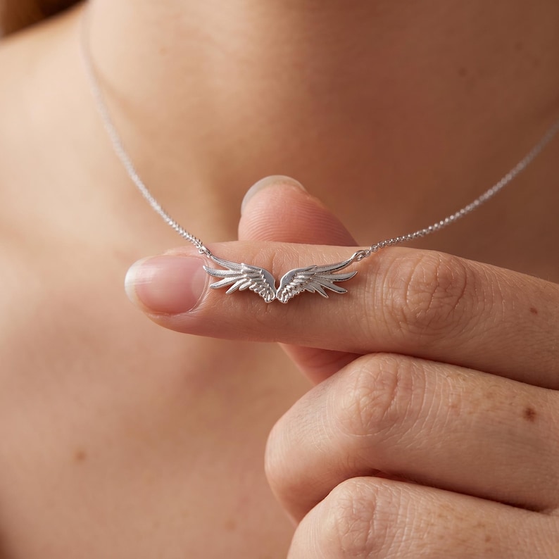 Dainty S925 sterling silver angel wing necklace with delicate guardian wings pendant, a minimalist silver necklace ideal for everyday wear and layered necklace styling. Polished rhodium plated finish, lightweight comfortable design, a meaningful pendant necklace for her, protection necklace, faith necklace, or thoughtful gift for women.