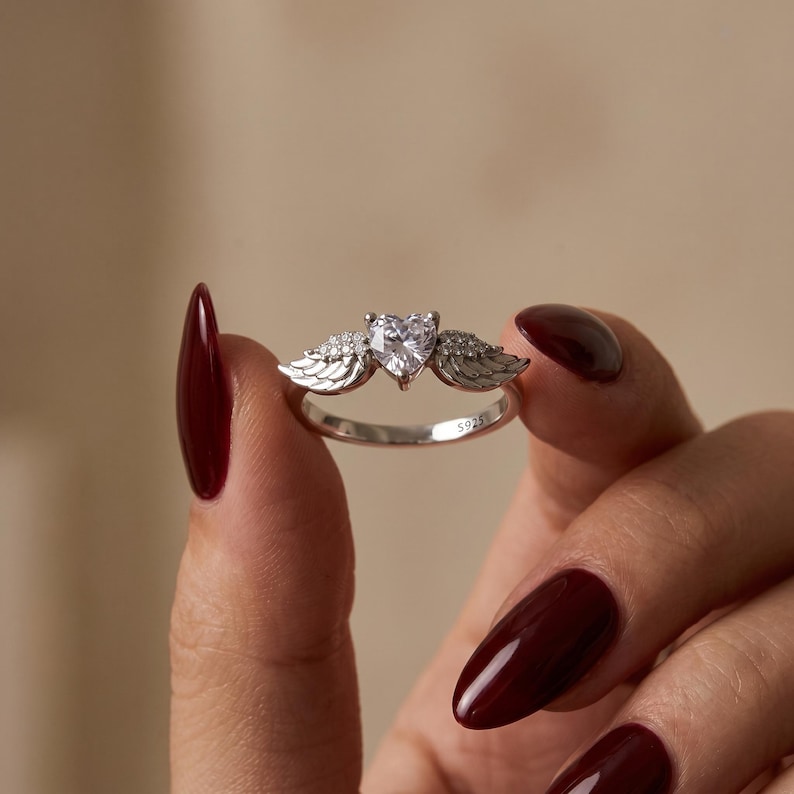 Angel wing heart ring in S925 sterling silver featuring a heart cut cubic zirconia between delicate feathered wings, a dainty promise ring for her and elegant cz ring perfect as a romantic gift for women, girlfriend, wife or best friend, ideal as a statement ring or friendship ring for everyday wear and special occasions.