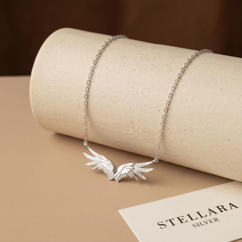 Sterling silver angel necklace featuring intricately detailed guardian wings pendant on a fine cable chain, a refined pendant necklace with a luminous rhodium finish. Symbolic protection necklace and memorial necklace, hand polished for brilliant shine, perfect for women who love minimalist jewelry and meaningful keepsakes.