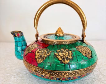 Tetera tibetana antigua de latón con mosaico de turquesa y coral y símbolos budistas.