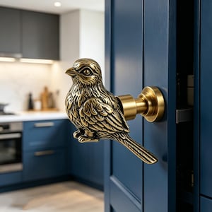Puede incluir: Un tirador de puerta de latón con forma de pájaro montado en una puerta azul. El tirador está intrincadamente detallado, representando un pájaro con plumas texturizadas y una base redonda. El tirador añade un toque decorativo a la puerta.