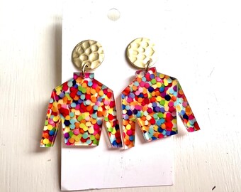 Op de afbeelding: Een paar kleurrijke confetti-patroon oorbellen met gouden accenten. De oorbellen zijn gevormd als een shirt met lange mouwen.
