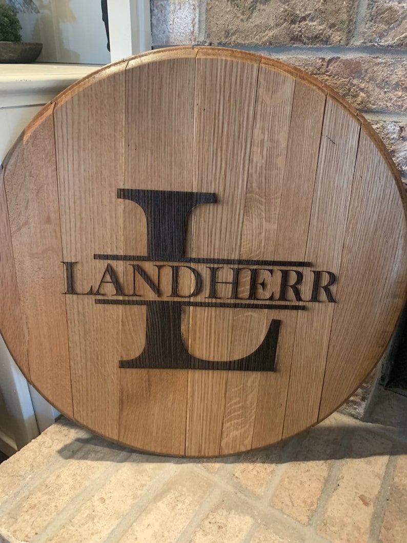 May include: A round wooden sign with a dark brown letter "L" and the name "LANDHERR" engraved in the wood.