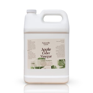 Puede incluir: Un bid&oacute;n de pl&aacute;stico blanco de un gal&oacute;n con una etiqueta marr&oacute;n que dice "Naturelle Grow Apple Cider Vinegar Gentle Shampoo" con un dise&ntilde;o floral. La etiqueta tambi&eacute;n incluye el texto "Prevents Herbal Conditioner, Supports healthy hair growth, for longer and fuller hair".