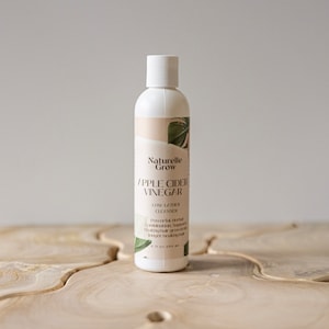 Puede incluir: Una botella blanca de limpiador de espuma baja de vinagre de sidra de manzana Naturelle Grow. La botella est&aacute; etiquetada con un dise&ntilde;o de hoja verde y el texto "Naturelle Grow Vinagre de sidra de manzana Limpiador de espuma baja Combinaci&oacute;n de hierbas potente que apoya el crecimiento saludable del cabello para un cabello m&aacute;s largo y saludable 250 ml (8 fl oz)"