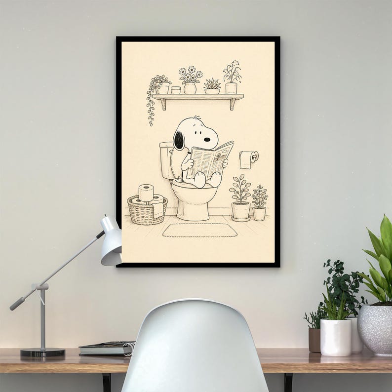 Puede incluir: Impresi&oacute;n enmarcada en negro que muestra a Snoopy sentado en un inodoro, leyendo un peri&oacute;dico. La ilustraci&oacute;n en blanco y negro presenta una estanter&iacute;a con plantas en macetas, una cesta de papel higi&eacute;nico y un rollo de papel higi&eacute;nico. El fondo es neutro.