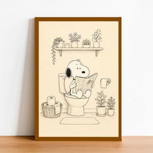 Puede incluir: Impresi&oacute;n enmarcada en blanco y negro de Snoopy leyendo un peri&oacute;dico en el inodoro. La ilustraci&oacute;n muestra un ba&ntilde;o con plantas en una estanter&iacute;a y en macetas. Un rollo de papel higi&eacute;nico est&aacute; en la pared.