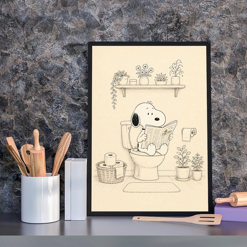 Puede incluir: L&aacute;mina enmarcada en negro que muestra a Snoopy sentado en el inodoro, leyendo un peri&oacute;dico. La escena del ba&ntilde;o incluye una estanter&iacute;a con plantas, un rollo de papel higi&eacute;nico y una cesta de papel higi&eacute;nico. La obra de arte es en blanco y negro.