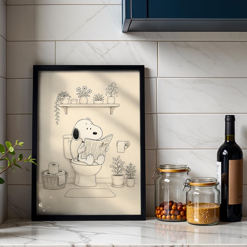 Puede incluir: Ilustraci&oacute;n en blanco y negro enmarcada de Snoopy leyendo un peri&oacute;dico en un inodoro. La obra de arte se presenta en un ba&ntilde;o, con una estanter&iacute;a con plantas encima y un rollo de papel higi&eacute;nico.