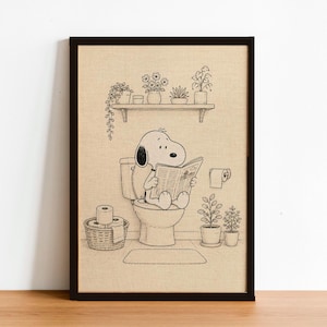 Puede incluir: Impresi&oacute;n enmarcada en negro que muestra a Snoopy sentado en un inodoro, leyendo un peri&oacute;dico. La ilustraci&oacute;n en blanco y negro incluye una estanter&iacute;a con plantas en macetas, un rollo de papel higi&eacute;nico y una peque&ntilde;a alfombra.