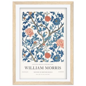 May include: Framed art print featuring a floral design with blue leaves and coral and blue flowers on a white background. The print includes the text "WILLIAM MORRIS" and "COTTON PRINTS EXHIBITION". The frame is light wood.