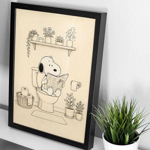 Puede incluir: L&aacute;mina enmarcada en negro que representa a Snoopy en el inodoro, leyendo un peri&oacute;dico. La ilustraci&oacute;n en blanco y negro incluye una estanter&iacute;a con plantas en macetas, una cesta de papel higi&eacute;nico y otra decoraci&oacute;n de ba&ntilde;o. Una pieza divertida y caprichosa.