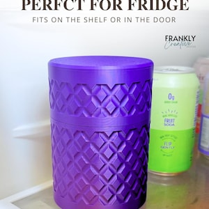 May include: A cylindrical purple container with a textured geometric diamond pattern on its exterior. The text above reads Compact Size PERFCT FOR FRIDGE FITS ON THE SHELF OR IN THE DOOR and FRANKLY Creative DESIGN. It sits on a glass shelf.