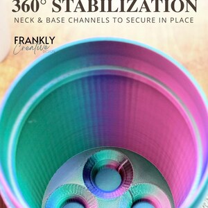 Puede incluir: Un recipiente cil&iacute;ndrico con un acabado degradado en rosa, azul y morado. La base interior presenta cuatro aberturas circulares. El texto en la parte superior dice: Precision Engineered 360&deg; STABILIZATION NECK & BASE CHANNELS TO SECURE IN PLACE FRANKLY Creative DESIGN.