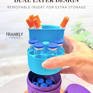 May include: A purple cylindrical storage container with a textured diamond pattern and a matching lid. It features a removable light blue dual-layer insert holding small glass vials with blue caps and orange-capped tools. Text reads Space Saver.