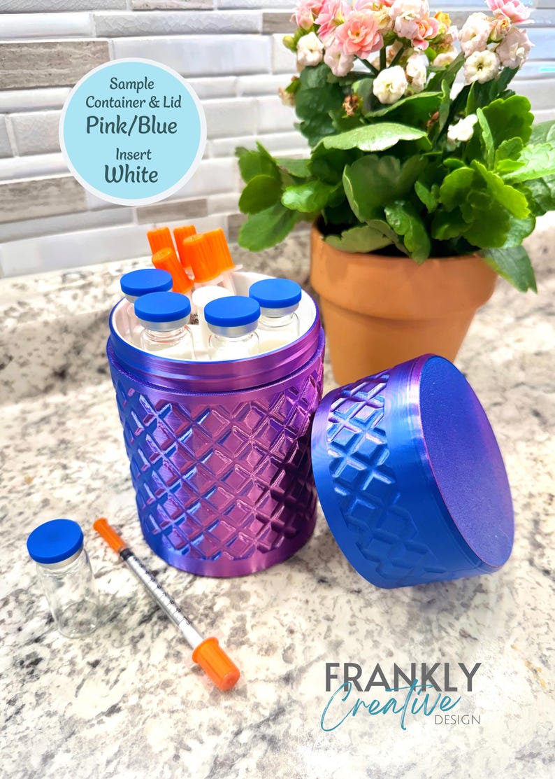 May include: A cylindrical container with a pink and blue gradient diamond-textured exterior and a matching lid. The container holds several small glass vials with blue caps and orange-capped syringes. Text reads: Sample Container & Lid Pink/Blue Insert White.