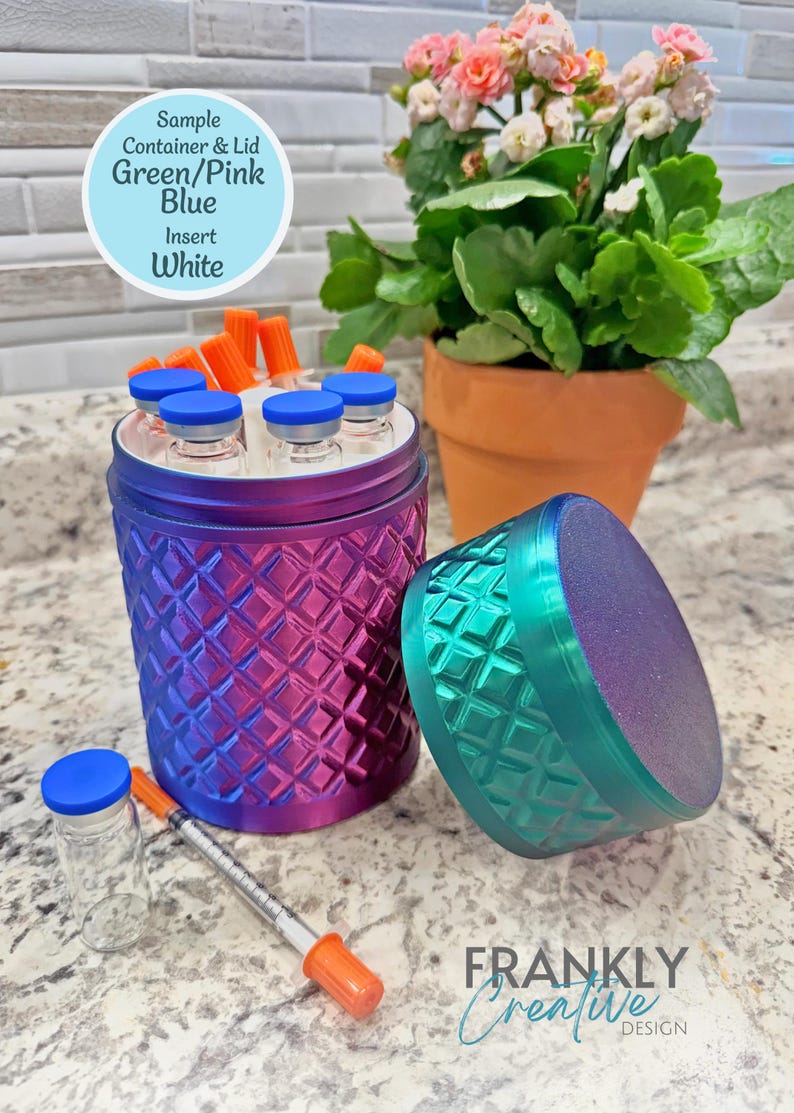 May include: A cylindrical container with a diamond-textured surface in a gradient of green, pink, and blue. It features a white interior insert, a matching lid, and holds several small glass vials with blue caps and orange-capped syringes.