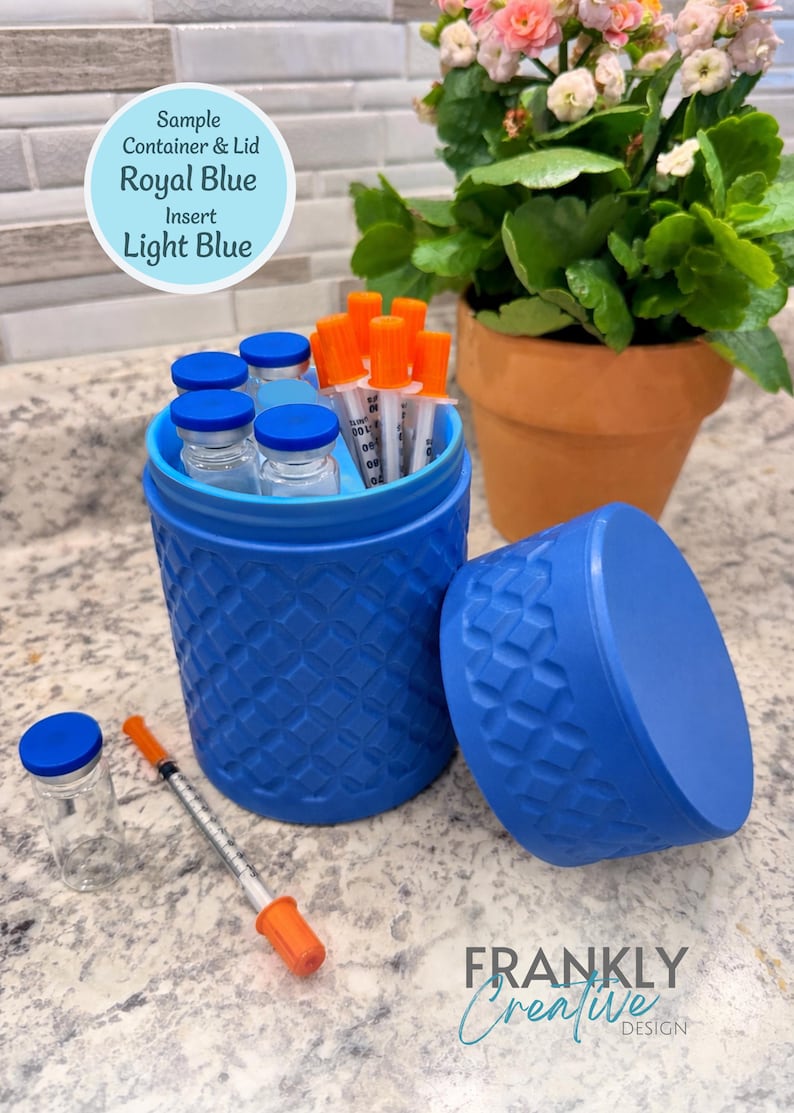 May include: A royal blue cylindrical container with a textured geometric pattern and a light blue interior insert. The container holds several clear glass vials with blue caps and syringes with orange caps. A matching lid sits beside it.
