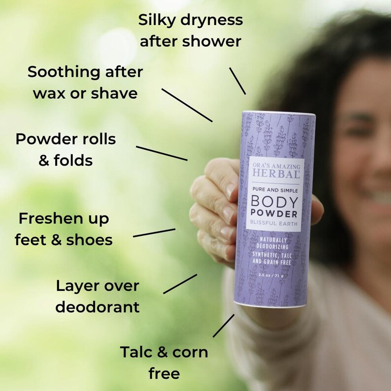 Puede incluir: Un envase cil&iacute;ndrico de polvos corporales con una etiqueta lavanda se sostiene frente a un fondo verde borroso. La etiqueta dice "ORA'S AMAZING HERBAL BODY POWDER" y enumera beneficios como "Silky dryness after shower".