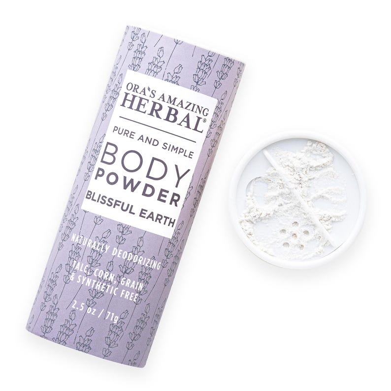 Puede incluir: Un envase cil&iacute;ndrico de polvos corporales y un peque&ntilde;o recipiente con polvos. El envase es de color lavanda con un estampado floral y el texto "ORA'S AMAZING HERBAL BODY POWDER BLISSFUL EARTH." El envase es de 71g.