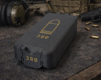 May include: A dark gray ammunition case with a gold bullet graphic and the number "380". The case is rectangular with a hinged lid. Several bullets and a handgun are visible in the background.
