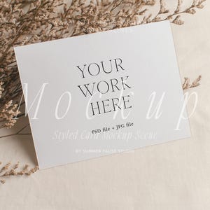May include: A white square card with the text "YOUR WORK HERE" in a minimalist font. The card is part of a mockup scene, with dried flowers and a neutral-toned background. The text "Styled Card Mockup Scene" is also visible.