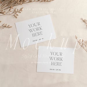 May include: A styled card mockup featuring two white cards with the text "YOUR WORK HERE" in a minimalist font. The cards are arranged on a beige fabric background, with dried floral accents. The image has a warm, neutral color palette.