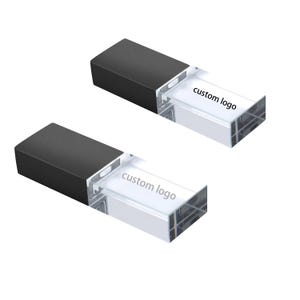 Könnte beinhalten: Zwei rechteckige USB-Sticks. Jeder Stick hat einen schwarzen Deckel und einen transparenten, rechteckigen Körper. Der Text "custom logo" ist auf dem transparenten Körper jedes Sticks aufgedruckt. Die Sticks befinden sich auf weißem Hintergrund.