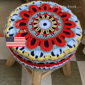 May include: A round wooden stool featuring a colorful, circular crochet cover with a mandala-inspired pattern in red, yellow, light blue, and white yarn. The text PDF PATTERN and @captain.hook.__ are visible, along with a small United States flag icon.