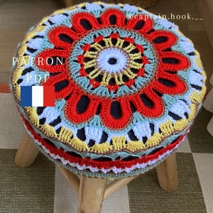 May include: A round wooden stool with a colorful, circular crochet cover featuring red, yellow, light blue, and white yarn patterns. The text PATRON PDF and a French flag icon are visible on the left, with @captain.hook.__ on the right.