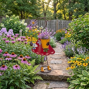 May include: A metal garden sculpture of a figure wearing a red dress with white scalloped trim and blue flower accents. The figure holds a yellow bucket filled with purple lavender flowers and features a purple flower detail at the top.